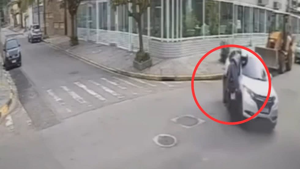 Câmeras de segurança registraram o momento em que criminosos se aproximaram do motociclista ferido para roubar seus objetos - Imagem: Reprodução