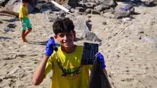 Participantes de mutirão recolhem resíduos na Praia Central de Mongaguá; entre os itens encontrados, um telefone fixo descartado na areia - Imagem: Thiago Teves/Prefeitura de Mongaguá